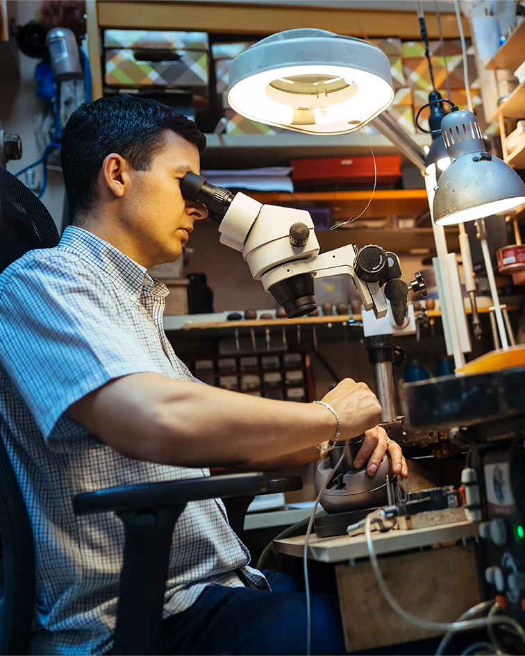 Artisan joaillier travaillant au microscope, fabrication artisanale de médailles Miles & Peaks